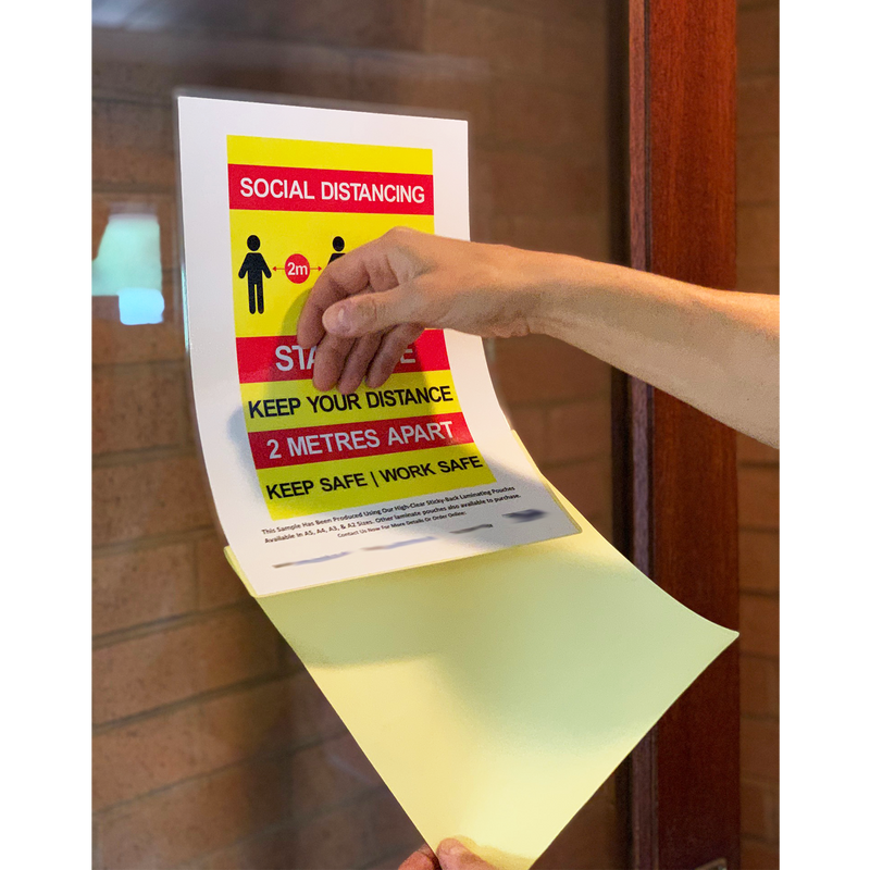 Load image into Gallery viewer, A person applying a sticky-back laminate pouch to a glass door.